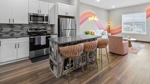 A modern kitchen with white cabinets, stainless steel appliances, and a central island with bar stools.