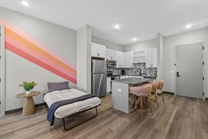 A modern apartment with a kitchenette, a dining area, and a bed.