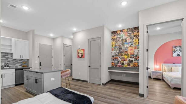 Une chambre moderne avec un lit, un petit bureau et un coin cuisine.