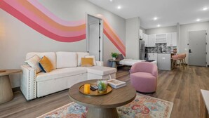 Un salon moderne avec un canapé blanc, un fauteuil rose et une table basse ronde.