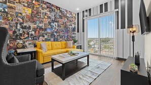 Un salon moderne avec un canapé jaune vif, une table basse et un mur recouvert d’un collage de pochettes d’albums.