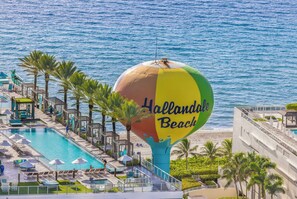 A beachside hotel with a large inflatable sign reading "Hollandale Beach," a swimming pool, lounge chairs, and palm trees. - ★★★★★ Modern Panoramic Escape With Views, NO RESORT&PARKING FEE. CHECK DETAILS (Hollywood)