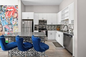 A modern kitchen with white cabinets, stainless steel appliances, and a black countertop.