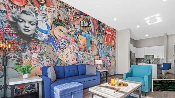 A living room with a vibrant graffiti wall, a blue sofa, a coffee table, and a kitchen in the background. - 1BR Spacious Apt Near Nashville’s Iconic Broadway (Nashville)