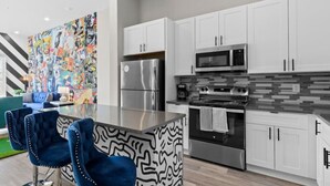 A modern kitchen with white cabinets, stainless steel appliances, and a colorful abstract mural on the wall. - 1BR Spacious Apt Near Nashville’s Iconic Broadway (Nashville)