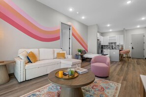 A modern living room with a white sectional sofa, a pink armchair, and a round coffee table with a tray. - Spacious 1BR for 4, Free WiFi | 8 Min to Broadway (Nashville)