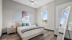 A bedroom with a bed, two bedside tables, a ceiling fan, a window, and a large mirror. - 1BR Getaway – Perfect Location for Music Lovers! (Nashville)