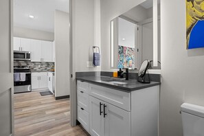 A modern kitchen with white cabinets, a black countertop, and a large mirror above the sink.