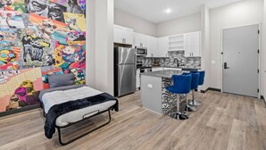 Un appartement moderne doté d’une kitchenette, d’un lit et d’une fresque murale aux couleurs vives.