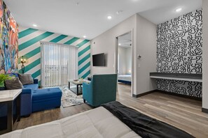 A modern hotel room with a large bed, a blue sofa, a small table, and a TV. - Modern 1BR Stay – Your Perfect Nashville Base (Nashville)