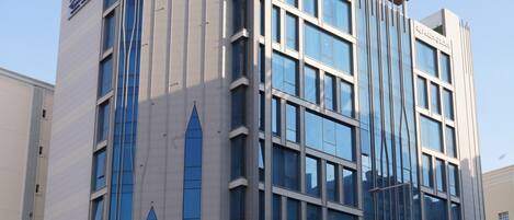 A modern hotel with a prominent vertical design, large windows, and a clear sky.