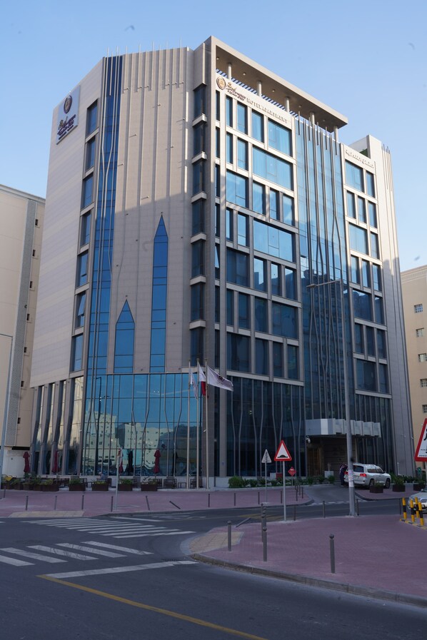 A modern hotel with a prominent vertical design, large windows, and a clear sky.