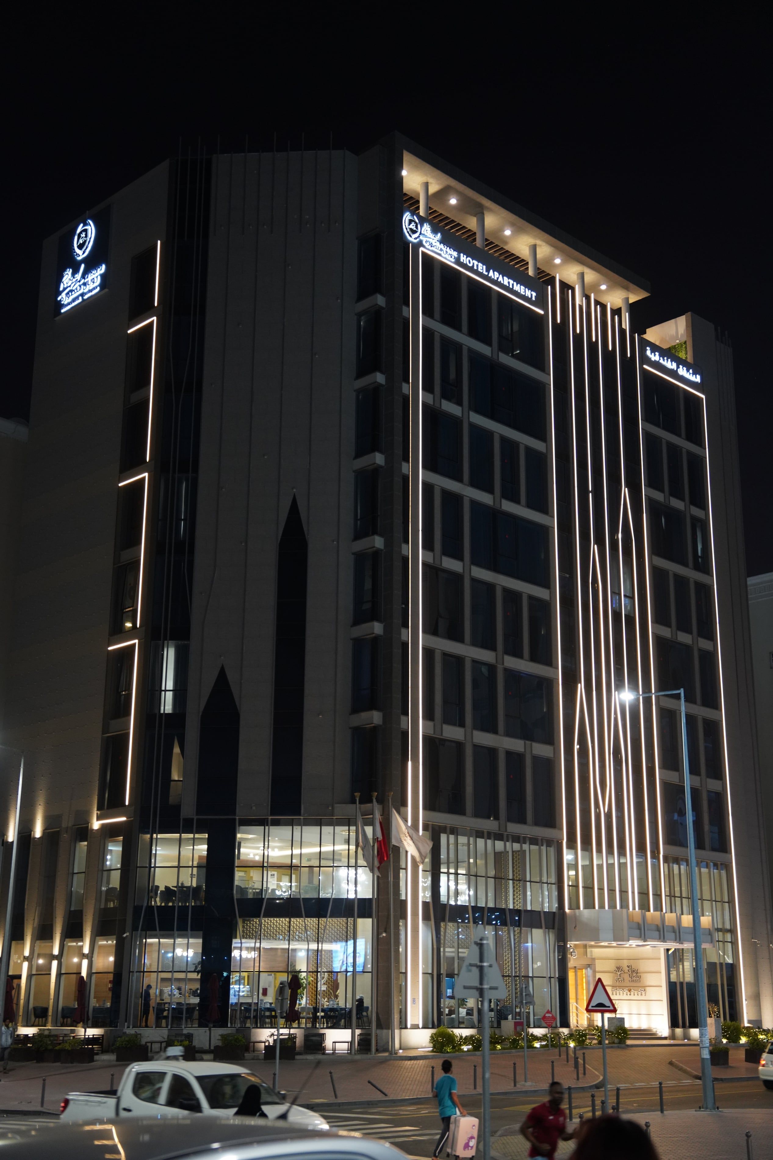 Un hotel moderno con una entrada destacada, ventanas amplias y una fachada bien iluminada.