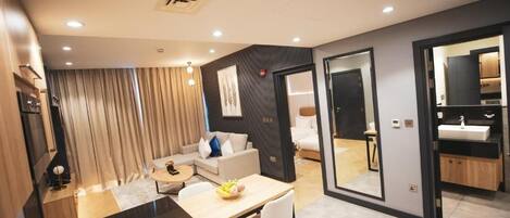 A modern hotel room with a dining area, a living space, and a bathroom.