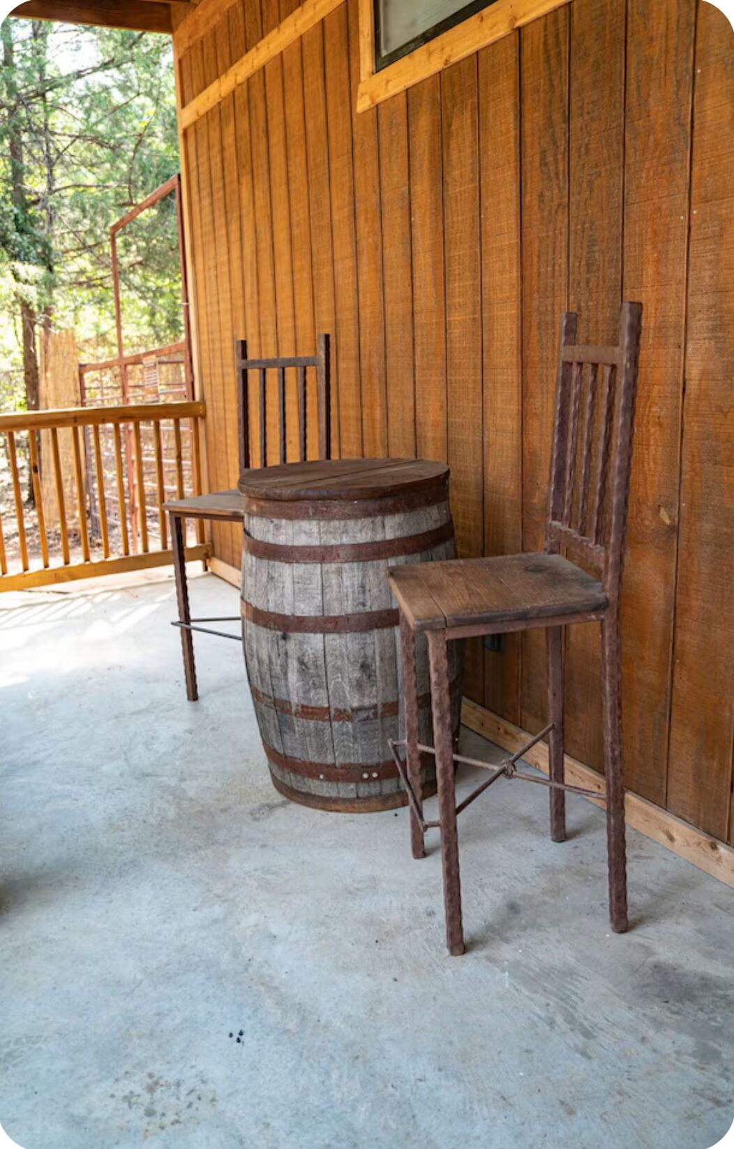 A rustic wooden porch with a wooden chair and a barrel.