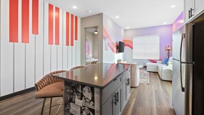 A modern kitchen with a central island, a dining area with a brown chair, and a living area with a sofa and a TV. - Perfect for Family Getaway - Mins from Music City! (Nashville)