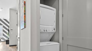 A laundry room with a stacked washer and dryer, a striped wall, and a door leading to another room. - Hip 1BR Hideaway - Quick Drive to Downtown Fun! (Nashville)