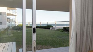 A view from a balcony with a grassy area and a building in the background. - Holiday Apartment, Lagoon Beach (Cape Town)