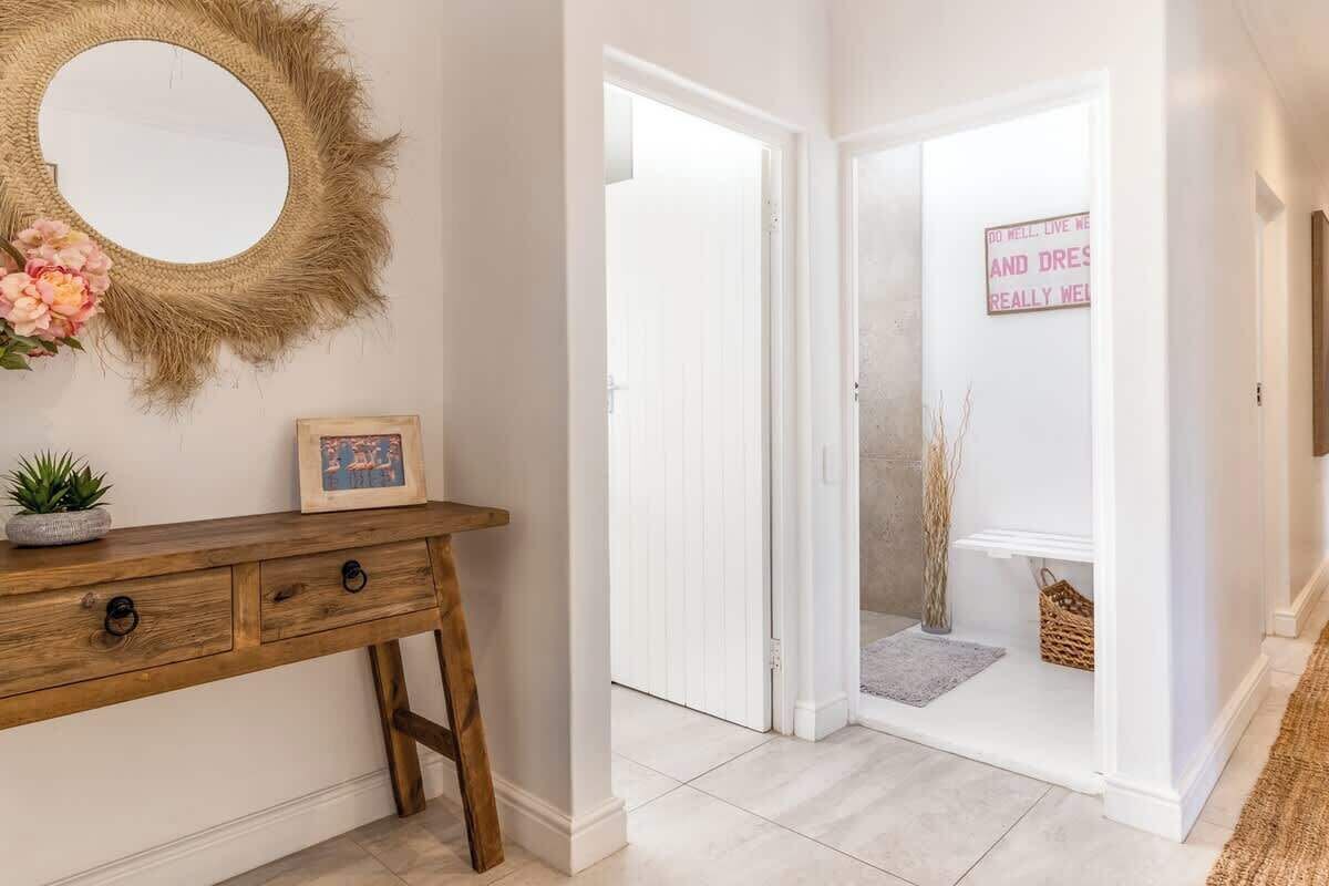 A hallway with a wooden console table, a round mirror, and a door leading to another room.