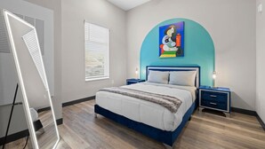 A modern bedroom with a bed, two bedside tables, a ceiling fan, and a large window with blinds.