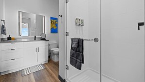 A modern bathroom with a white vanity, a toilet, and a shower area.