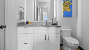 A modern bathroom with a white vanity, a sink, and a toilet.