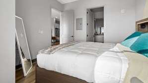 A bedroom with a bed, a bedside table, a mirror, and a wardrobe.
