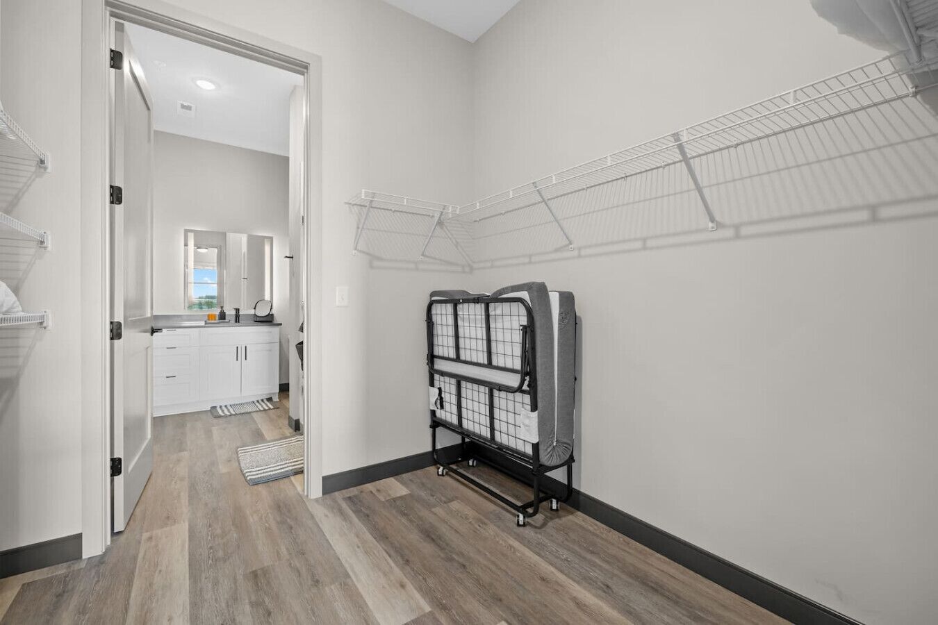 A laundry room with a drying rack, a walk-in closet, and a wooden floor.