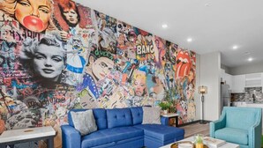 Een woonkamer met een blauwe bank, een salontafel en een kleurrijke muurschildering.