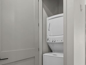 A compact, white laundry room with a front-loading washing machine and dryer.