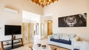 Una sala de estar con televisión, sofá, mesa de centro y obras de arte.