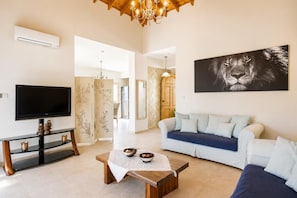A living room with a television, sofa, coffee table, and artwork.