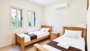 Un dormitorio con dos camas, una mesita de noche y un aire acondicionado.