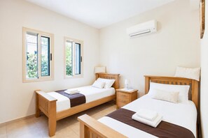Ein Schlafzimmer mit zwei Betten, einem Nachttisch und einer Klimaanlage.