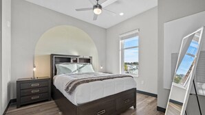 Un dormitorio con cama, mesita de noche y ventilador de techo.