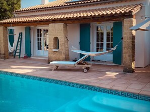 A poolside area with a hammock, a sun lounger, and a tiled pool with a decorative edge. - Colorful LA CASITA house in Uzès city center with swimming pool (Uzès)