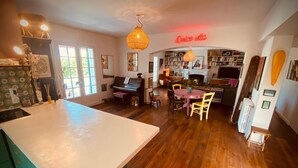 Une cuisine chaleureuse avec un piano, un plancher en bois et un coin repas comprenant des chaises et une table.