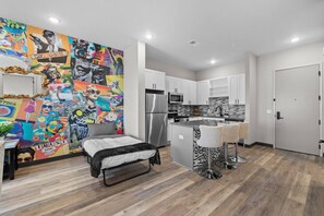 A modern kitchen with white cabinets, a stainless steel refrigerator, and a microwave. - Stay Close to the Action – Cozy 1BR Nash Retreat (Nashville)