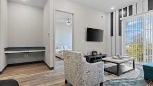 Un salon moderne avec un canapé, une table basse, un téléviseur et un balcon offrant une vue agréable.