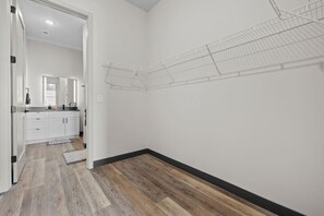A hallway with a wooden floor, white walls, and a metal wire shelf. - Stay Close to the Action – Cozy 1BR Nash Retreat (Nashville)