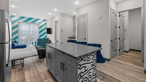 Una cocina moderna con una isla central, armarios grises y un banco tapizado en azul.