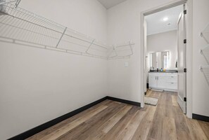 Un couloir doté d’un plancher en bois, de murs blancs et d’une porte donnant sur un espace cuisine.