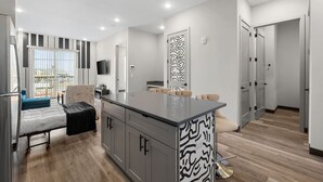 Una cocina moderna con una isla central, armarios grises y un salpicadero con diseño.
