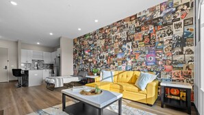 A modern living room with a yellow sofa, a coffee table, and a wall covered with album covers.