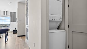 Une buanderie équipée d’un lave-linge et d’un sèche-linge à chargement frontal, d’une petite table avec une bouteille, et offrant une vue sur l’extérieur par une fenêtre.