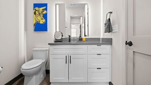 A modern bathroom with a white toilet, a sink with a mirror above it, and a towel rack. - 1BR Nash Apt Near Downtown & Best Attractions! (Nashville)