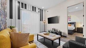 A modern living room with a sofa, coffee table, and a TV. - 1BR Nash Apt Near Downtown & Best Attractions! (Nashville)