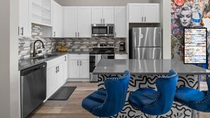 A modern kitchen with white cabinets, a stainless steel refrigerator, and a microwave.