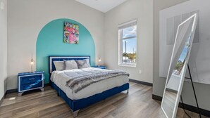 A bedroom with a bed, a nightstand, a wall-mounted air conditioner, and a window with a view.