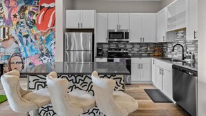 A modern kitchen with white cabinets, stainless steel appliances, and a black countertop. - Urban Oasis 1BR - Quick Access to Downtown Nash! (Nashville)